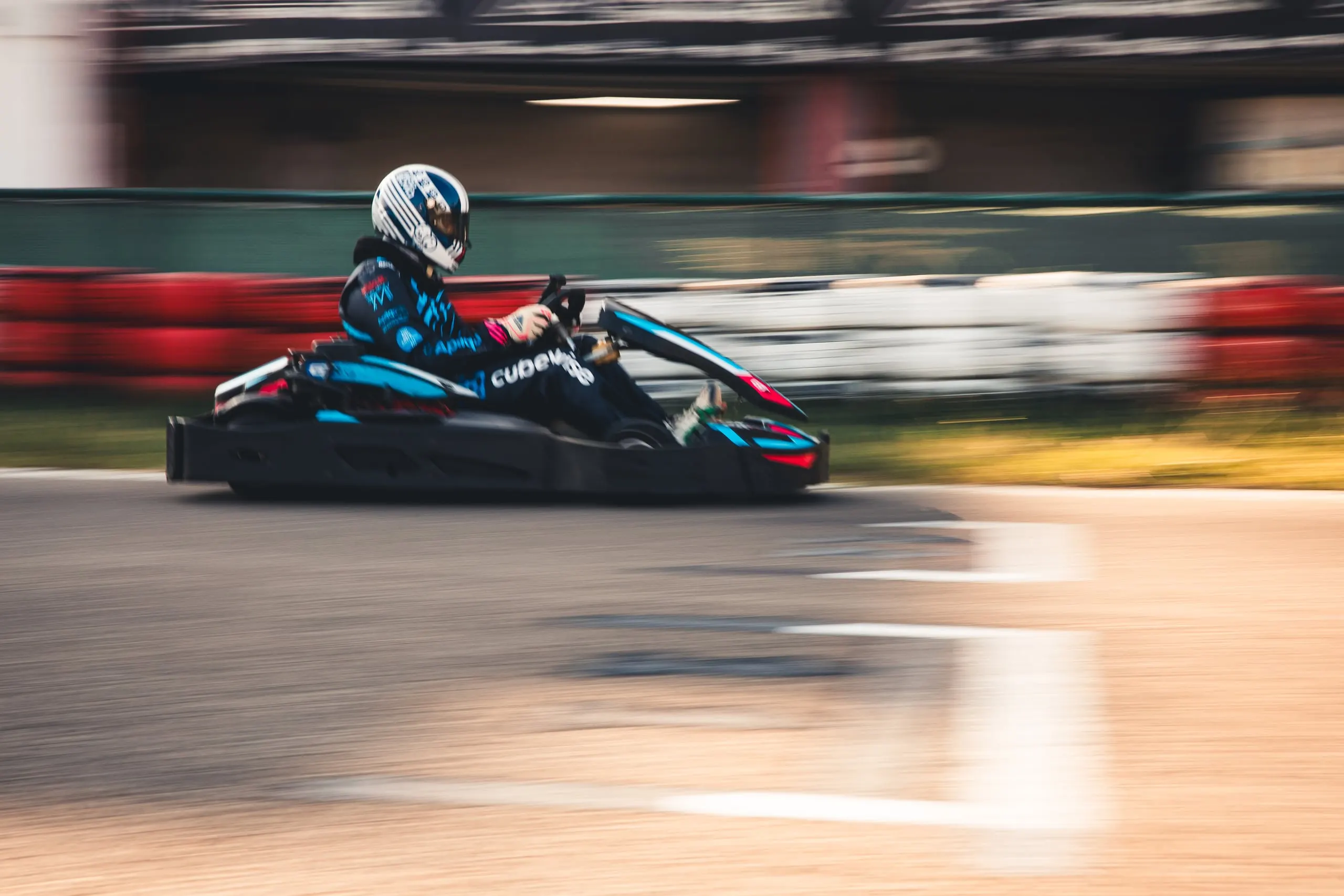 Kart em movimento, piloto com capacete branco e azul